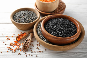Bowls with different lentils on wooden table