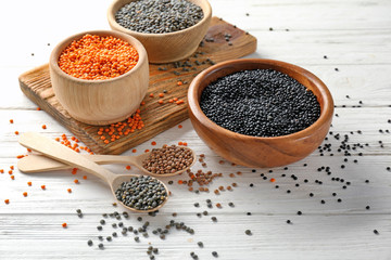 Bowls with different lentils on wooden table