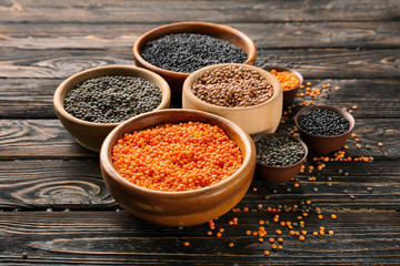 Bowls with different lentils on wooden table