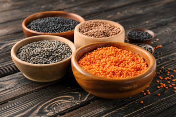 Bowls with different lentils on wooden table