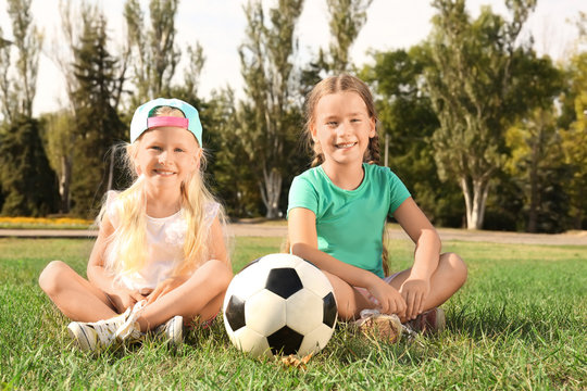 Cute children with soccer ball on lawn