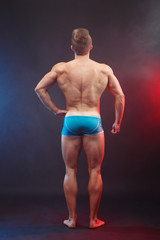 Fototapeta na wymiar Studio shoot of young handsome muscular fit handsome shirtless man with perfect body, view from the back. Vertical image. Power, strength, excellent body, bodybuilding, sports concept