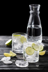 Selective focus composition with gin and tonic cocktail served with citrus on  wooden table with pieces of ice