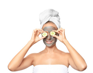 Young woman with facial mask and cucumber slices on white background