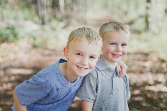 Smiling brothers stop to take a photo during nature walk in woods