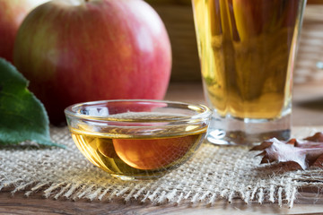 Apple cider vinegar in a glass bowl, with apples in the background