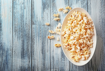 Plate with popcorn on wooden table