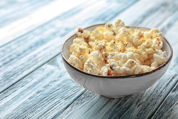 Bowl with popcorn on wooden table