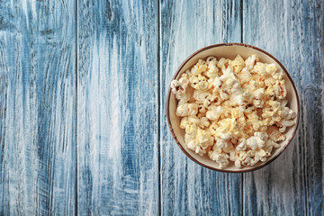 Bowl with popcorn on wooden table