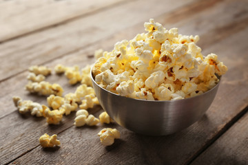 Bowl with popcorn on wooden table
