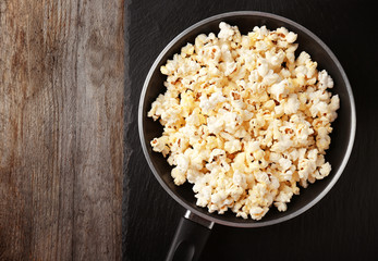 Frying pan with popcorn on wooden table