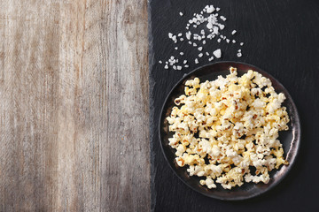 Plate with popcorn on wooden table