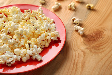 Plate with popcorn on wooden table