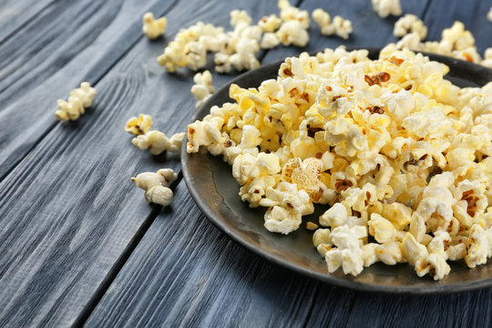Plate with popcorn on wooden table