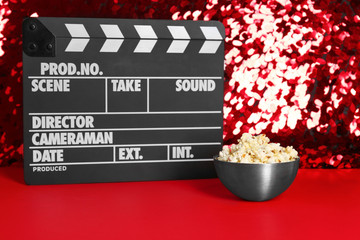 Movie clapper and bowl of popcorn on red carpet