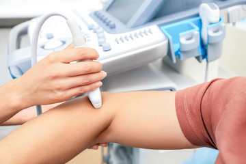 Doctor conducting ultrasound examination of patient's elbow in clinic