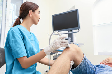 Doctor conducting ultrasound examination of patient's knee in clinic