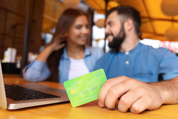 Young couple with laptop and credit card in cafe. Internet shopping concept