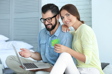 Obraz premium Young couple with laptop and credit card at home. Internet shopping concept