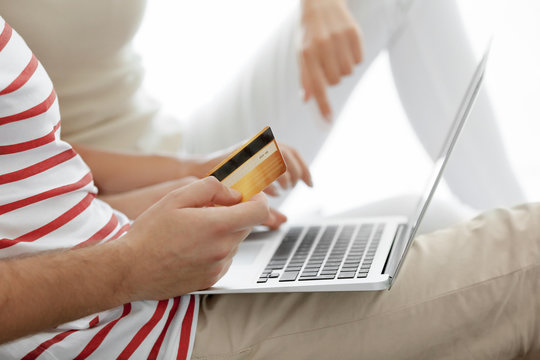 Couple with laptop and credit card on light background. Internet shopping concept