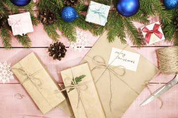 Christmas holiday decor. Border decorated blue balls or bauble and gift boxes wrapped craft paper,  fir branches, pine cones. Xmas card made rustic style in creative concept.
