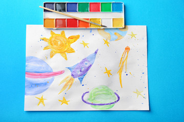 Child's painting of rocket in space on blue background