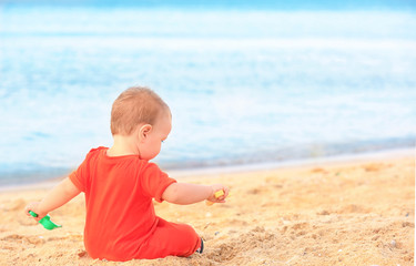 Cute baby boy playing with toys on beach