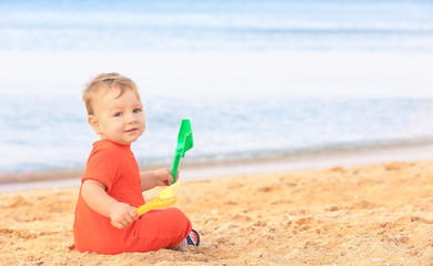 Cute baby boy playing with toys on beach