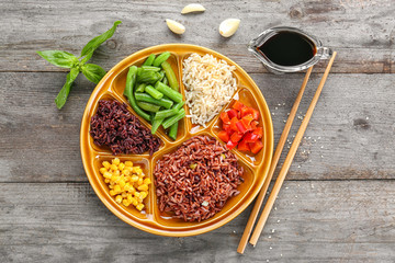 Plate with brown rice and vegetables on wooden table