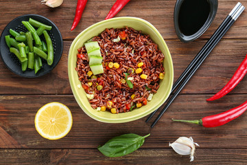 Bowl with brown rice and vegetables on wooden table