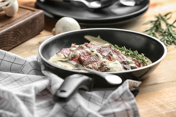 Frying pan with steak Diane on table