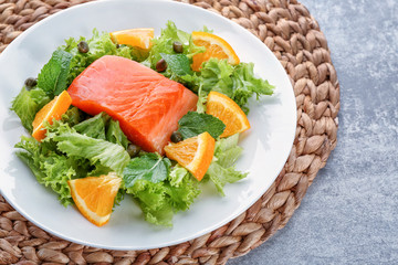 Plate with delicious salmon salad on table