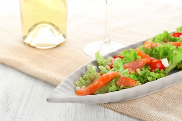 Plate with delicious salmon salad on table