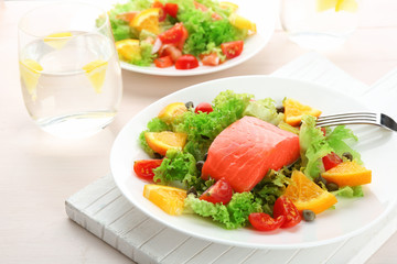 Plate with delicious salmon salad on table