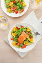 Plates with delicious salmon salad on table