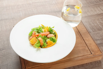 Plate with delicious salmon salad on table