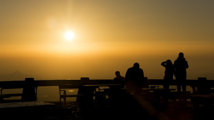 Fototapeta na wymiar Hot yellow sky dusring sunset. Silhouette of people sitting on bench.