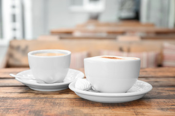 Cups of delicious coffee on wooden table, closeup