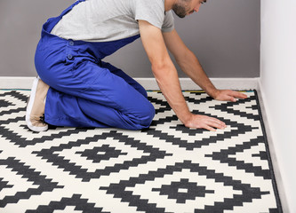 Male worker laying carpet indoors