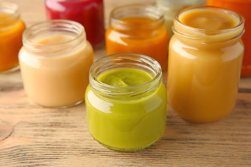 Assortment of jars with tasty baby food on wooden table