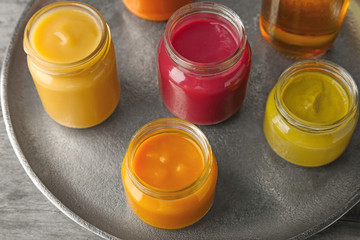 Assortment of jars with tasty baby food on plate