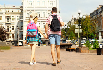 Happy young tourists walking on street in city