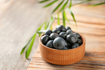 Bowl with fresh acai berries on wooden table, closeup