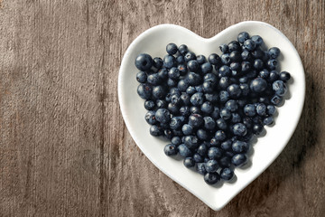 Plate with fresh acai berries on wooden table