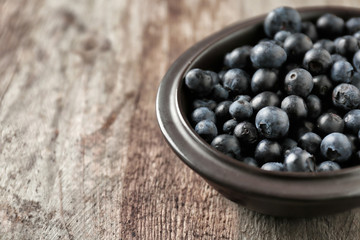 Bowl with fresh acai berries on wooden table, closeup