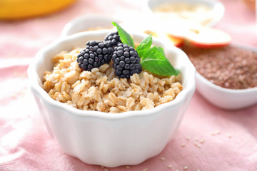 Tasty oatmeal with berries in bowl on table