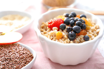 Tasty oatmeal with berries in bowl on table