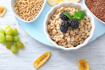 Tasty oatmeal with berries in bowl on table