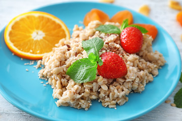 Plate of nutritious oatmeal with strawberry on table, close up