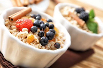 Tasty oatmeal with berries in bowl, close up